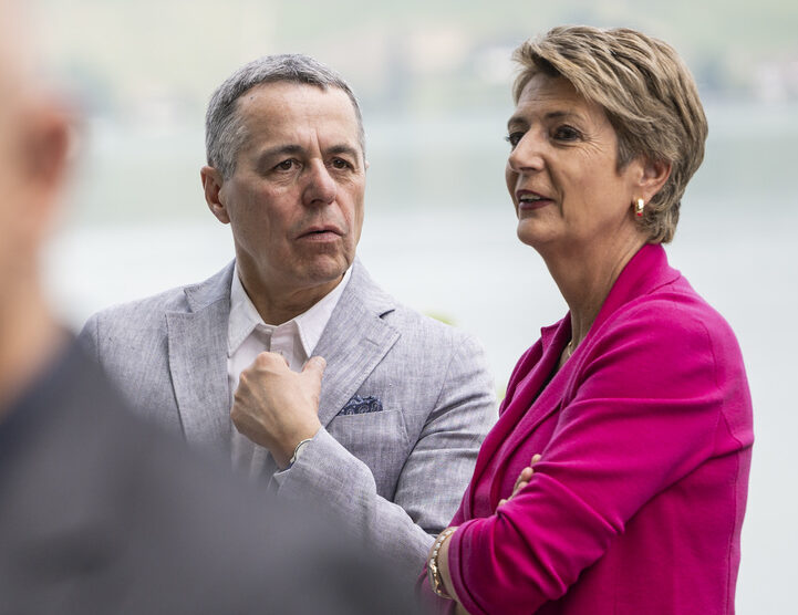 Waehrend Bundespraesident Alain Berset, links, zu Medienvertretern spricht, diskutieren Bundesraetin Karin Keller-Sutter, rechts, und Bundesrat Ignazio Cassis mit dem Murtesee im Hintergrund, am Rand der Bundesratsreise, am Donnerstag, 29. Juni 2023 in Murten. (KEYSTONE/Alessandro della Valle)