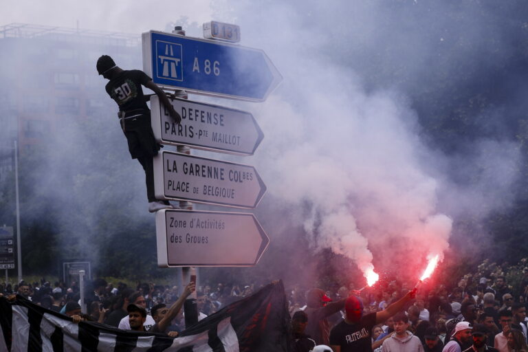epa10717471 A person climbs a traffic sign as others hold flares during a march in the memory of 17-year-old Nahel, who was killed by French Police in Nanterre, near Paris, France, 29 June 2023. Violence broke out after the police fatally shot a 17-year-old during a traffic stop in Nanterre on 27 June. According to the French interior minister, 31 people were arrested with 2,000 officers being deployed to prevent further violence. EPA/YOAN VALAT