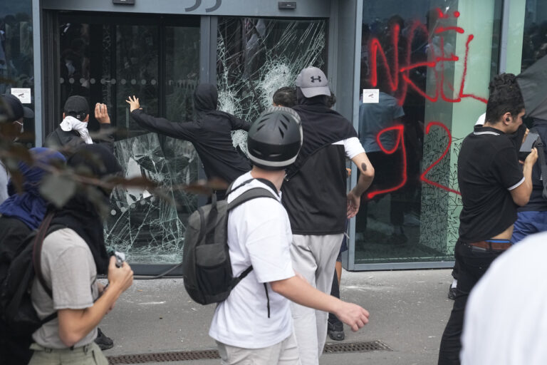 Youths smash a window after a march for Nahel, Thursday, June 29, 2023 in Nanterre, outside Paris. The killing of 17-year-old Nahel during a traffic check Tuesday, captured on video, shocked the country and stirred up long-simmering tensions between young people and police in housing projects and other disadvantaged neighborhoods around France. (AP Photo/Michel Euler)