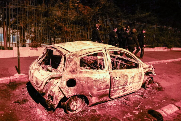 epa10720140 Policemen walk next to a burned car destroyed during clashes between protesters and riot police in Nanterre, near Paris, France, France, early 01 July 2023. Violence broke out all over France after police fatally shot a 17-year-old teenager during a traffic stop in Nanterre on 27 June. EPA/MOHAMMED BADRA