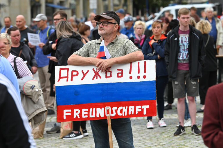 01.07.2023, Sachsen-Anhalt, Magdeburg: Ein Teilnehmer der AfD-Kundgebung hält ein Schild in den Farben von Russland mit der deutsch-russischen Aufschrift 