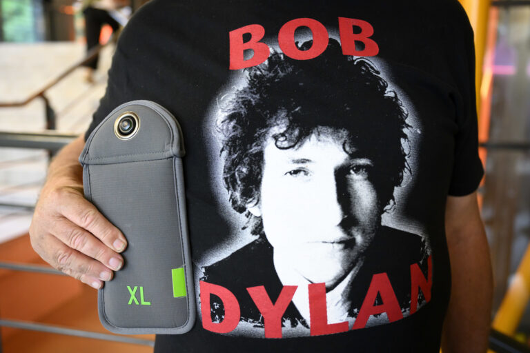 A fan of American singer-songwriter Bob Dylan shows his mobile phone sealed in a bag before the start of the concert on the stage of the Stravinski hall at the 57th Montreux Jazz Festival (MJF), in Montreux, Switzerland, Saturday, July 1, 2023. For the first time in Montreux, the folk poet has insisted that no spectators are allowed to use their mobile phones. These are sealed in a bag before the start of the concert. Photos and videos are also banned for the media and organisers. (KEYSTONE/Laurent Gillieron)