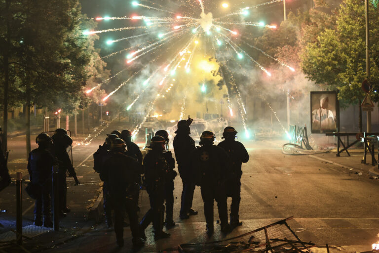 FILE - Police stand amid firecrackers on the third night of protests sparked by the fatal police shooting of a 17-year-old driver in the Paris suburb of Nanterre, France, Friday, June 30, 2023. The June 27 shooting of the teen, identified as Nahel, triggered urban violence and stirred up tensions between police and young people in housing projects and other neighborhoods. After more than 3,400 arrests and signs that the violence is now abating, France is once again facing a reckoning. (AP Photo/Aurelien Morissard, File)