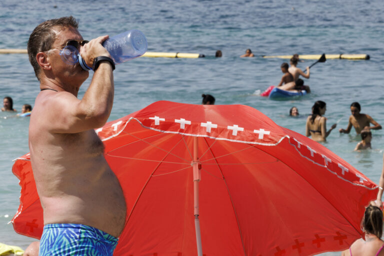 Joel drinks water on the Baby plage on the bank of the Geneva lake, in Geneva, Switzerland, Tuesday, July 11, 2023. A heat wave has just entered Geneva and the day the thermometers will mark temperatures above 38 degrees. (KEYSTONE/Salvatore Di Nolfi)