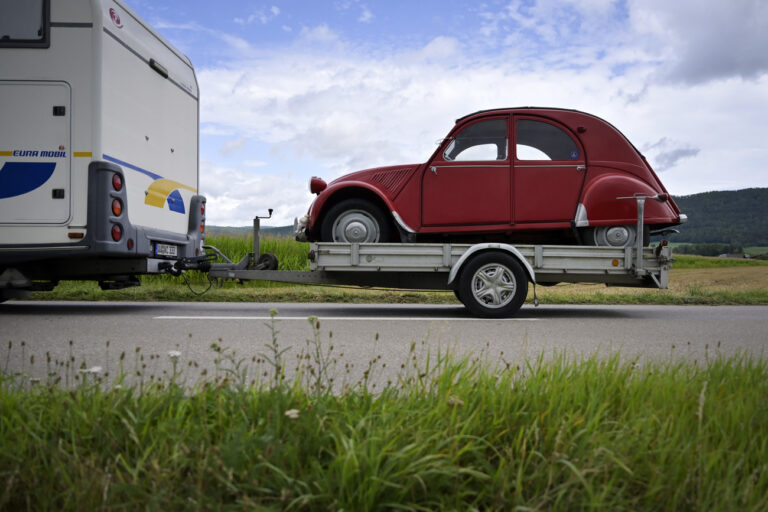 Ein Citroen 2CV wird auf einem Anhaenger zum 24. Welttreffen der Freunde des 2CV in Vicques gefahren, am Dienstag, 25. Juli 2023. Vom 25. bis zum 30. Juli 2023 werden rund 3000 Fahrzeuge und 6000 bis 7000 Teilnehmer im Jura erwartet. (KEYSTONE/Georgios Kefalas)