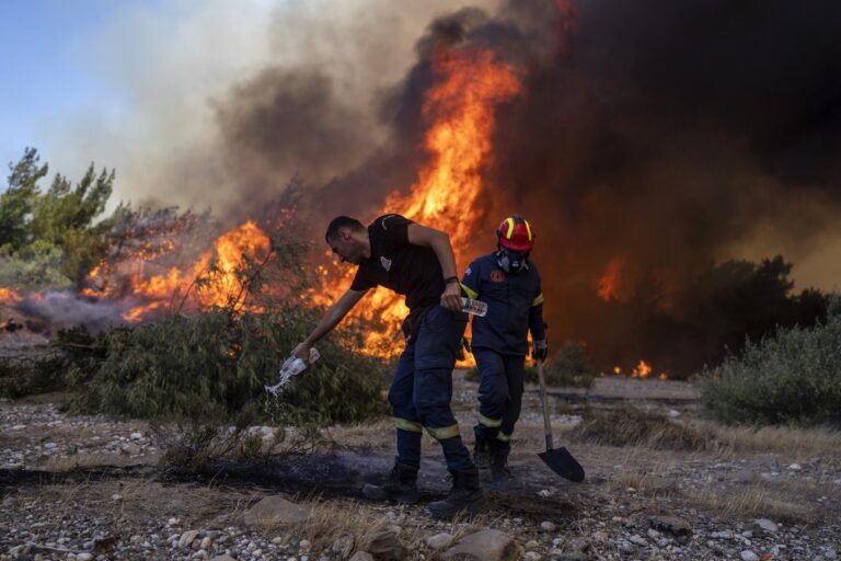 A firefighter uses a bottle to drop water over a burnt plant as the flames approaching in Vati village, on the Aegean Sea island of Rhodes, southeastern Greece, on Tuesday, July 25, 2023. A third successive heat wave in Greece pushed temperatures back above 40 degrees Celsius (104 degrees Fahrenheit) across parts of the country Tuesday following more nighttime evacuations from fires that have raged out of control for days. (AP Photo/Petros Giannakouris)