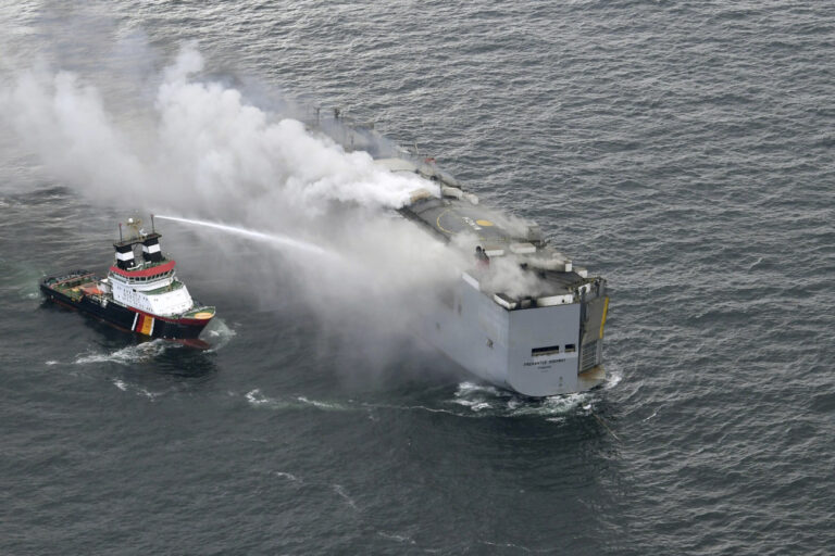A boat hoses the smoke from a fire which broke out on a freight ship in the North Sea, about 27 kilometers (17 miles) north of the Dutch island of Ameland, Wednesday, July 26, 2023. A fire on the freight ship Fremantle Highway, carrying nearly 3,000 cars, was burning out of control Wednesday in the North Sea, and the Dutch coast guard said it was working to save the vessel from sinking close to an important habitat for migratory birds. (Kustwacht Nederland/Coast Guard Netherlands via AP)