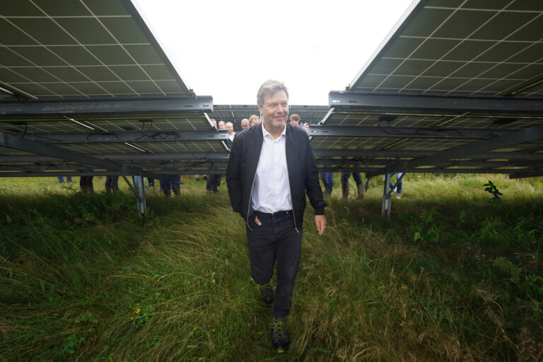 03.08.2023, Schleswig-Holstein, Klein Rheide: Robert Habeck (Bündnis 90/Die Grünen), Bundesminister für Wirtschaft und Klimaschutz, geht an Solarmodulen während seines Besuchs im Solarpark Klein Rheide vorbei. Habeck hat die biodiversitätsfördernde Agri-PV-Anlage im Rahmen seiner Sommertour in seinem Wahlkreis Flensburg-Schleswig besucht. Foto: Marcus Brandt/dpa +++ dpa-Bildfunk +++ (KEYSTONE/DPA/Marcus Brandt)