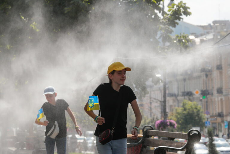 epa10802899 People walk under a pipe spraying water on Khreshchatyk street on a hot sunny day in Kyiv, Ukraine, 16 August 2023. EPA/SERGEY DOLZHENKO