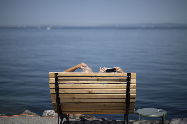 Eine Frau macht ein Foto, am Freitag, 18. August 2023, am Bodensee in Rorschach. Die kommenden Tage sollen grossen Teile der Schweiz eine Hitzewelle bringen. (KEYSTONE/Gian Ehrenzeller)