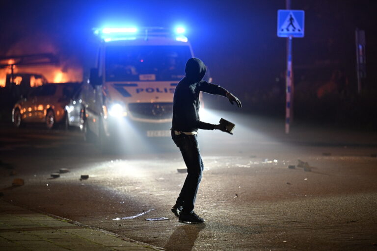 epa10839220 A protester throws a stone after a large number of cars were set on fire on Ramels vag in Rosengard, in Malmo, Sweden, 04 September 2023. According to the police's website, the incident is classified as a violent riot and stone throwing. EPA/JOHAN NILSSON SWEDEN OUT