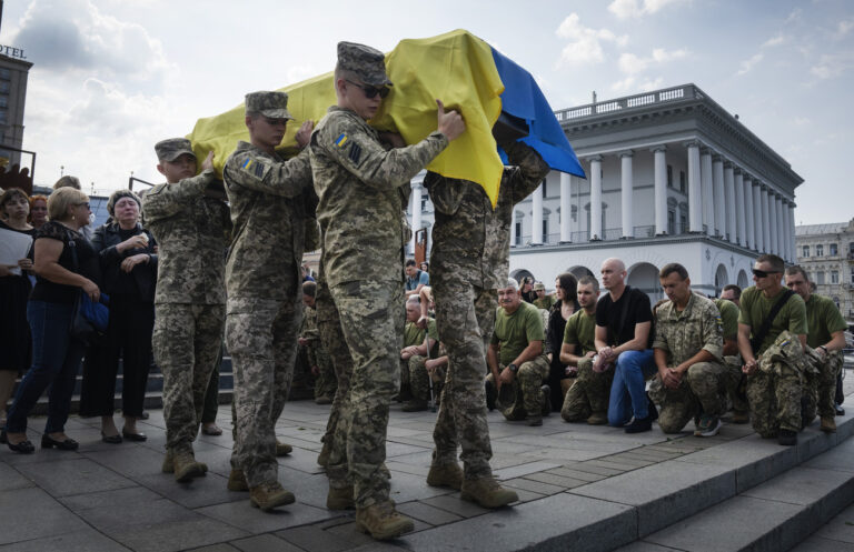 People kneel as soldiers carry the coffin of Ukrainian serviceman Sergiy Yarmolenko who was killed in a battle with the Russian troops, during the funeral ceremony in Independence square in Kyiv, Ukraine, Thursday, Sept. 14, 2023. (AP Photo/Efrem Lukatsky)