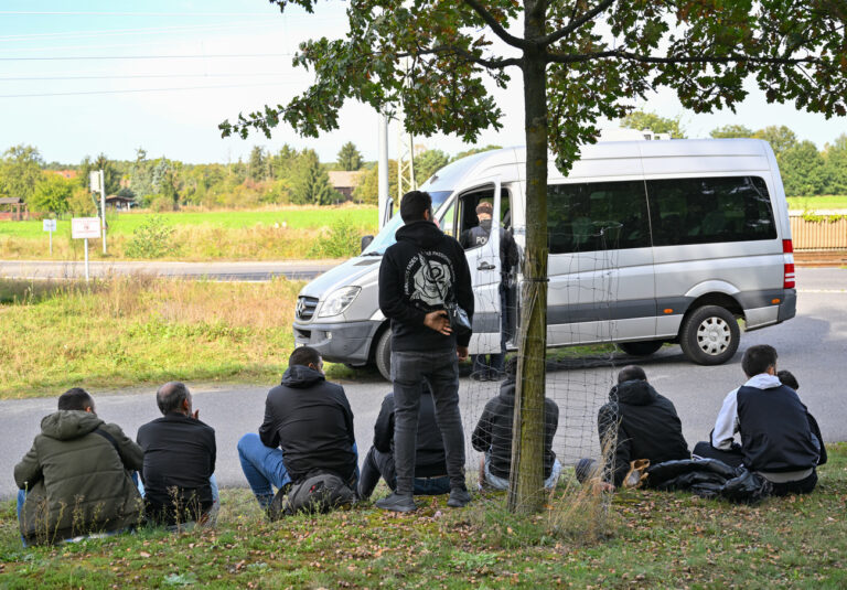 11.10.2023, Brandenburg, Roggosen: Unerlaubt eingereiste Migranten warten, nachdem sie durch die Bundespolizei nahe Forst (Lausitz) aufgegriffen wurden. Bei mehreren Einsätzen im brandenburgischen Forst und Umgebung hat die Bundespolizei am Mittwoch mindestens 64 unerlaubt eingereiste Migranten aufgegriffen. Darunter waren zwei Frauen und sechs unbegleitete Minderjährige, die übrigen waren meist junge Männer, wie der zuständige Sprecher der Bundespolizei, Jens Schobranski, sagte. (zu dpa 