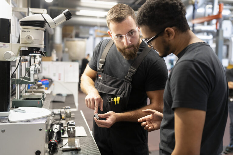 Zwei SFS-Mitarbeiter besprechen und kontrollieren die Qualitaet eines in der SFS-Fabrik hergestellten Teils, fotografiert am Montag, 9. Oktober 2023 in Heerbrugg. SFS ist ein Unternehmen fue applikationskritische Praezisionskomponenten und Baugruppen, mechanische Befestigungssysteme, Qualitaetswerkzeuge und Bewirtschaftungsloesungen. (KEYSTONE/Gaetan Bally)..