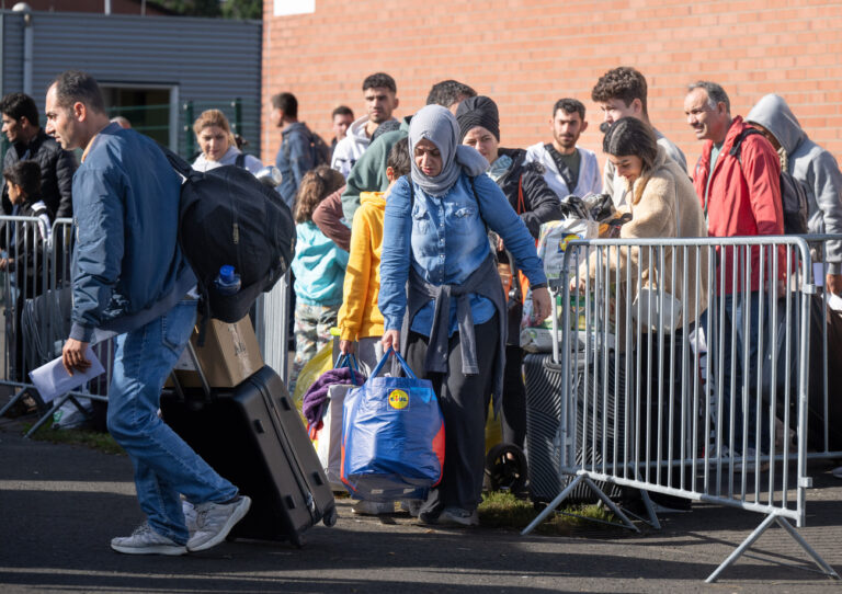 ARCHIV - 11.10.2023, Hessen, Gießen: Flüchtlinge gehen in der hessischen Erstaufnahmeeinrichtung (HEAE) zu einem wartenden Bus. Sie werden auf kommunale Einrichtungen verteilt. (zu dpa «Hessen zahlt Kommunen weitere 50 Millionen Euro für Flüchtlinge») Foto: Boris Roessler/dpa - ACHTUNG: Verwendung nur im vollen Format +++ dpa-Bildfunk +++ (KEYSTONE/DPA/Boris Roessler)