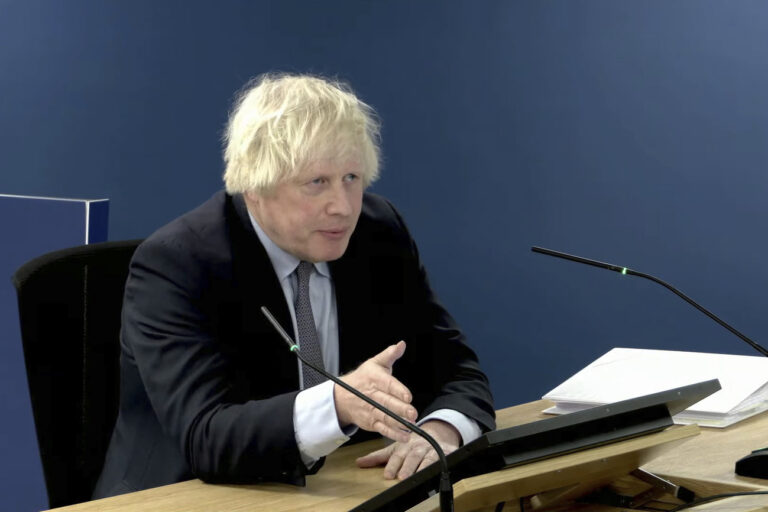 This image taken from the UK COVID-19 Inquiry live stream shows former British prime minister Boris Johnson giving evidence at Dorland House in London, Wednesday Dec. 6, 2023, during its second investigation (Module 2) exploring core UK decision-making and political governance. Johnson began two days of questioning under oath by lawyers for the judge-led inquiry about his initial reluctance to impose a national lockdown in early 2020 and other fateful decisions. (UK COVID-19 Inquiry via AP)