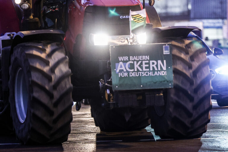 18.12.2023, Sachsen, Leipzig: Einer von mehreren Landwirten fährt mit seinem Traktor und einem Protestplakat am frühen Morgen durch den beginnenden Berufsverkehr. Aus Protest gegen die vorgesehene Streichung von Steuervergünstigungen durch die Ampel-Koalition wollen Landwirte am Montag in Berlin mobil machen. Unter dem Motto «Zu viel ist zu viel» ist am Vormittag eine Kundgebung am Brandenburger Tor geplant. Foto: Jan Woitas/dpa +++ dpa-Bildfunk +++ (KEYSTONE/DPA/Jan Woitas)