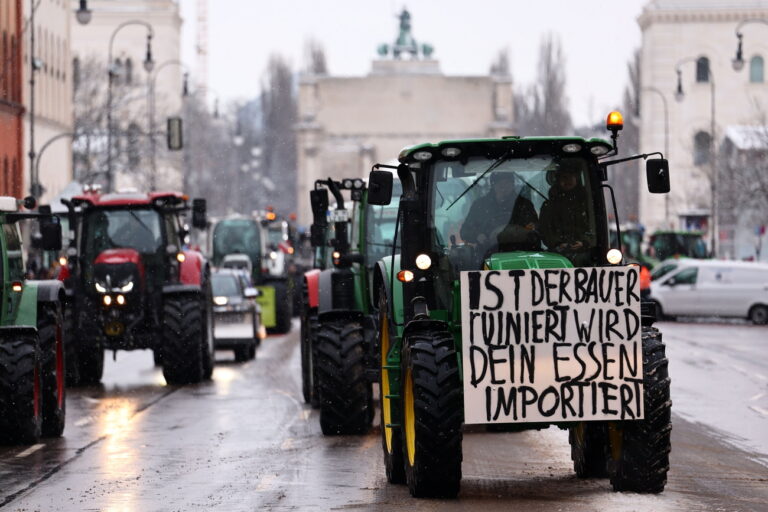 epa11064132 A banner hangs on a tractor that reads, ‘If the farmers are ruined, your food will be imported' as German farmers demonstrate along Leopold Street during a nationwide farmers' strike, in Munich, Germany, 08 January 2024. Farmers went on strike nationwide in Germany, in protest against the federal government's agricultural policy. EPA/ANNA SZILAGYI