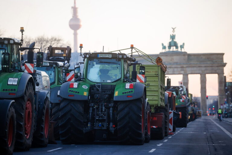 epa11065401 Tractors stand queued up in front of the Brandenburg Gate with the TV tower in the background during a nationwide farmers' strike, in Berlin, Germany, 09 January 2024. Farmers went on strike nationwide in Germany, in protest against the federal government's agricultural policy. EPA/CLEMENS BILAN