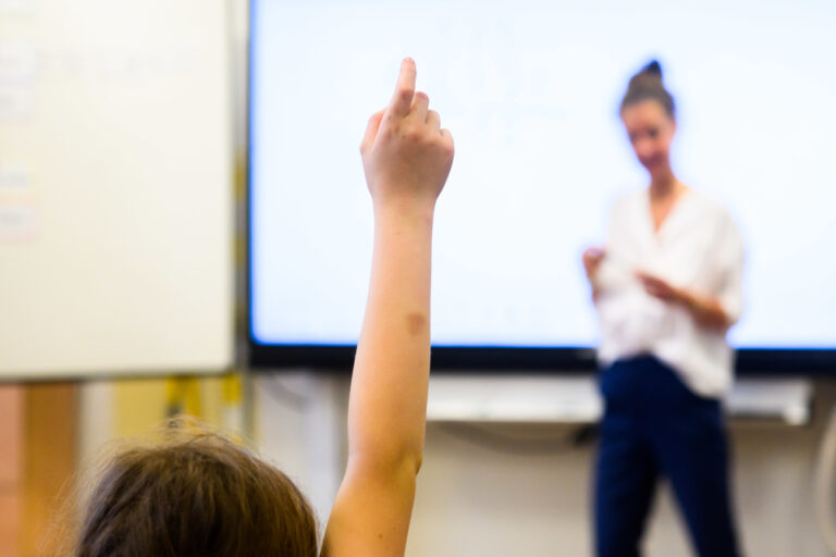 ARCHIV - 17.08.2023, Niedersachsen, Hannover: ILLUSTRATION - Ein Schüler meldet sich per Handzeichen während eine Lehrerin vor einer digitalen Schultafel steht. (zu dpa: «Bildungsressort: Lehrer sollen Arbeitszeit erfassen können») Foto: Julian Stratenschulte/dpa +++ dpa-Bildfunk +++ (KEYSTONE/DPA/Julian Stratenschulte)