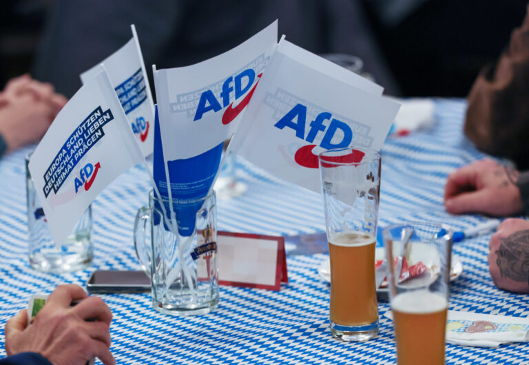 14.02.2024, Bayern, Osterhofen: Beim Politischer Aschermittwoch der AfD stehen Fahnen der Partei auf dem Biertisch. Der politische Aschermittwoch geht auf einen Viehmarkt im 19. Jahrhundert im niederbayerischen Vilshofen zurück. Foto: Daniel Löb/dpa +++ dpa-Bildfunk +++ (KEYSTONE/DPA/Daniel Löb)