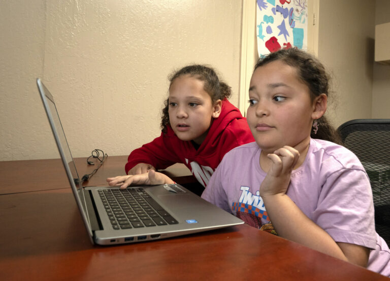 Amaya Cates,10, left, watches her sister, Ayiana, 8, work on a computer at the African American Family and Cultural Center, in Oroville, Calif., Feb. 8, 2024. A measure aimed at transforming how California spends money on mental health will go before voters in March as the state continues to grapple an unabated homelessness crisis. The 14-year-old community center that offers a variety of programs including after school programs, art classes, anger management sessions could be forced to close if it loses it's funding from Butte County. (AP Photo/Rich Pedroncelli)
