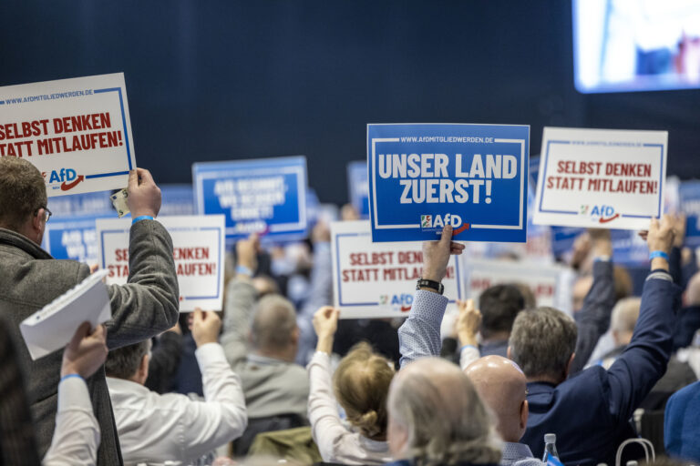 24.02.2024, Nordrhein-Westfalen, Marl: Delegierte des 21. Landesparteitags der Alternative für Deutschland NRW halten Schilder mit Aufschriften: «Afd Mitglied werden, Unser Land zuerst» in die Luft. Begleitet von lautstarken Gegenprotesten und massiven Sicherheitsvorkehrungen der Polizei hat am Samstag in Marl der Landesparteitag der nordrhein-westfälischen AfD begonnen. Foto: Thomas Banneyer/dpa +++ dpa-Bildfunk +++ (KEYSTONE/DPA/Thomas Banneyer)