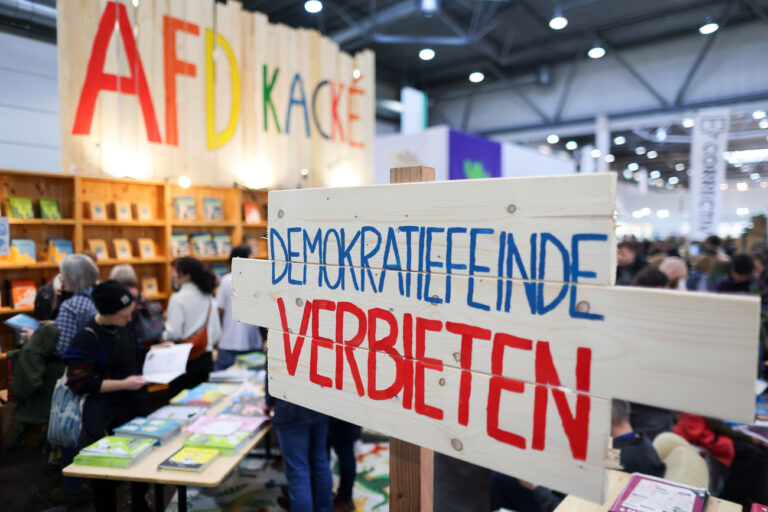 23.03.2024, Sachsen, Leipzig: Schilder mit der Aufschrift «Demokratiefeinde verbieten» und «AFD Kacke» stehen am Stand des Katapult-Verlages auf der Leipziger Buchmesse. Auf dem Frühjahrstreffen der Buchbranche präsentieren sich über 2000 Aussteller aus 40 Ländern mit ihren Neuheiten. Foto: Jan Woitas/dpa +++ dpa-Bildfunk +++ (KEYSTONE/DPA/Jan Woitas)