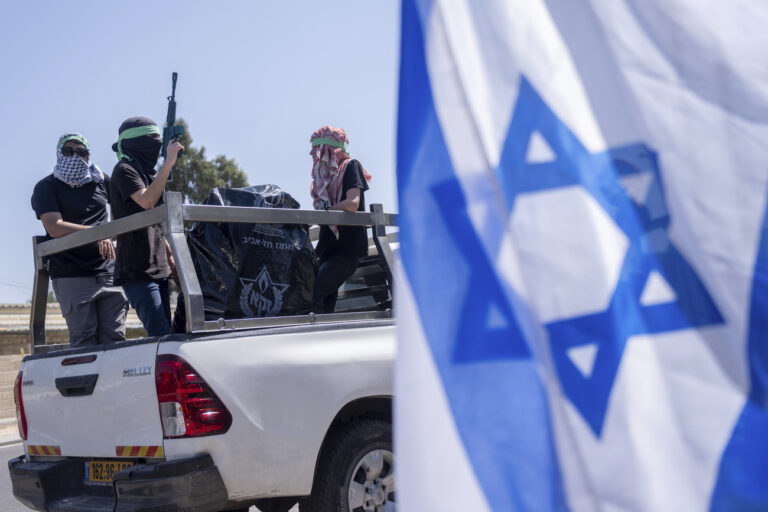 Israeli protesters dressed in Hamas militants' costumes demonstrate outside of the entrance of the UNWRA (United Nations Relief and Works Agency for Palestine Refugees in the Near East) headquarters, the main U.N. agency providing aid in the Gaza Strip, during a protest, in Jerusalem, Wednesday, April 3, 2024. (AP Photo/Ohad Zwigenberg)