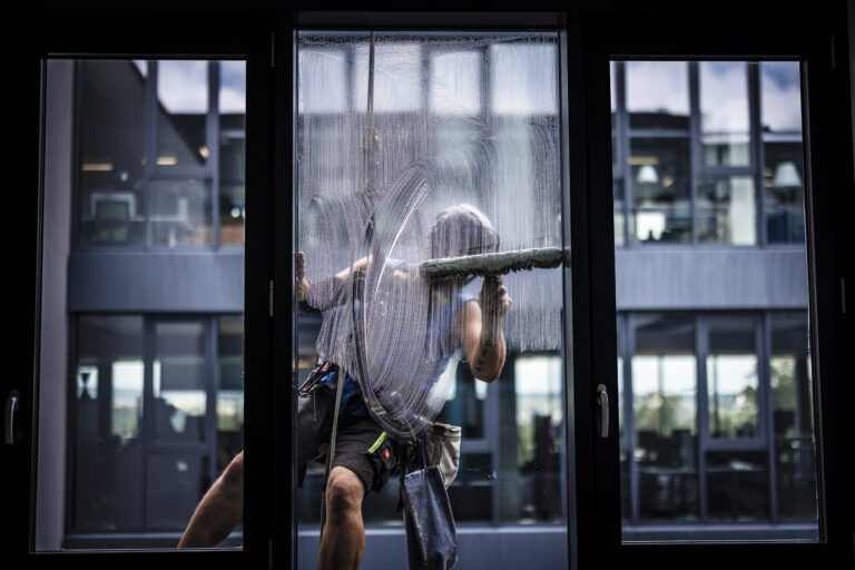 A rope access technician, roped up, cleans the windows of an office building in Bern, Switzerland on Monday, June 24, 2024. (KEYSTONE/Michael Buholzer).