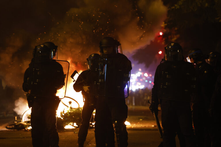 Police officers stand by burning bicycles during tensions near Republique plaza following the second round of the legislative elections, Sunday, July 7, 2024 in Paris. A coalition of the French left that quickly banded together to beat a surging far right in legislative elections won the most seats in parliament but not a majority, according to polling projections Sunday, a stunning outcome that threatens to plunge the country into political and economic turmoil. (AP Photo/Aurelien Morissard)