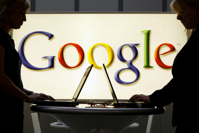 FILE - In this April 17, 2007 file photo, exhibitors work on laptop computers in front of an illuminated sign of the Google logo at the industrial fair Hannover Messe in Hanover, Germany. (AP Photo/Jens Meyer, File)