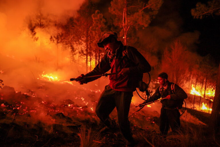 epa11621197 Two firefighters fight a forest fire in Intiyaco near Villa Berna, Cordoba province, Argentina, 23 September 2024. Firefighters continue to battle the flames in several parts of Cordoba province, where forest fires have been raging for several days. According to the spokesperson for the provincial Climate Risk Secretariat, Roberto Schreiner, four fires remain active and two people have been arrested on suspicion of starting a fire. EPA/STR