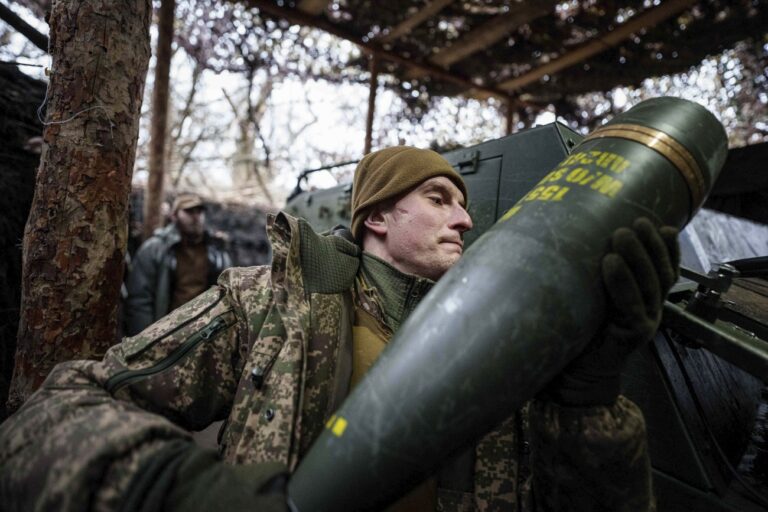 A Ukrainian serviceman with the Azov brigade carries a 155mm artillery shell to a self-propelled howitzer before firing toward Russian front-line positions in Ukraine's Donetsk region on Thursday, Jan. 23, 2025. (AP Photo/Evgeniy Maloletka)