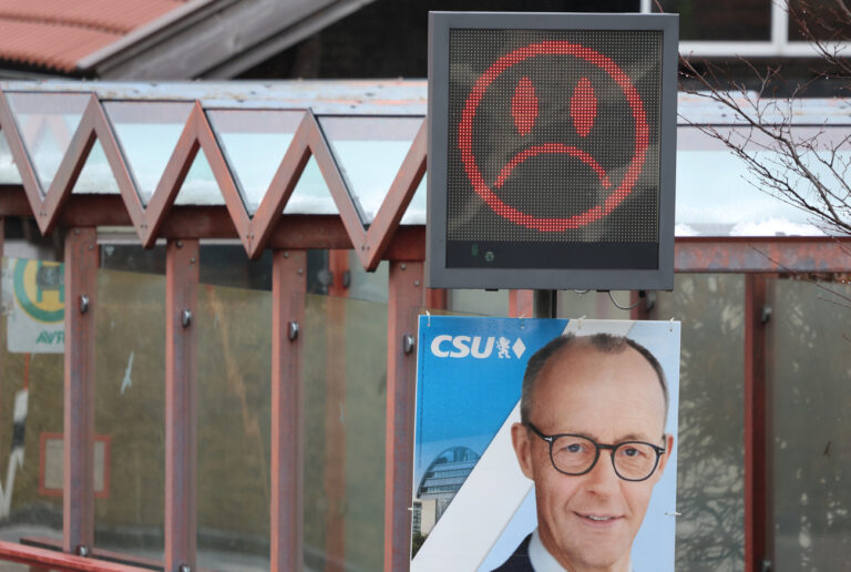 31.01.2025, Bayern, Nesselwang: Ein Emoji mit heruntergezogenen Mundwinkeln, welcher Autofahrern zu schnelles Fahren signalisiert, ist über einem Wahlplakat der CSU mit einem Foto von Friedrich Merz, dem CDU-Vorsitzenden und Chef der Unions-Bundestagsfraktion, zu sehen. Foto: Karl-Josef Hildenbrand/dpa - ACHTUNG: Nur zur redaktionellen Verwendung im Rahmen der aktuellen Berichterstattung über die Bundestagswahl 2025 +++ dpa-Bildfunk +++ (KEYSTONE/DPA/Karl-Josef Hildenbrand)