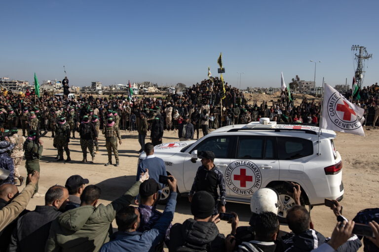 epa11897702 Palestinians and Izz ad-Din al-Qassam brigade fighters stand around Red Cross vehicles during the handover ceremony of three Israeli hostages to the Red Cross, in Khan Yunis, southern Gaza Strip, 15 February 2025. Hamas on 15 February released three Israeli hostages in exchange for 369 Palestinians detained in Israeli prisons. Israel and Hamas implemented the first phase of a hostage release and ceasefire deal on 19 January 2025. EPA/HAITHAM IMAD