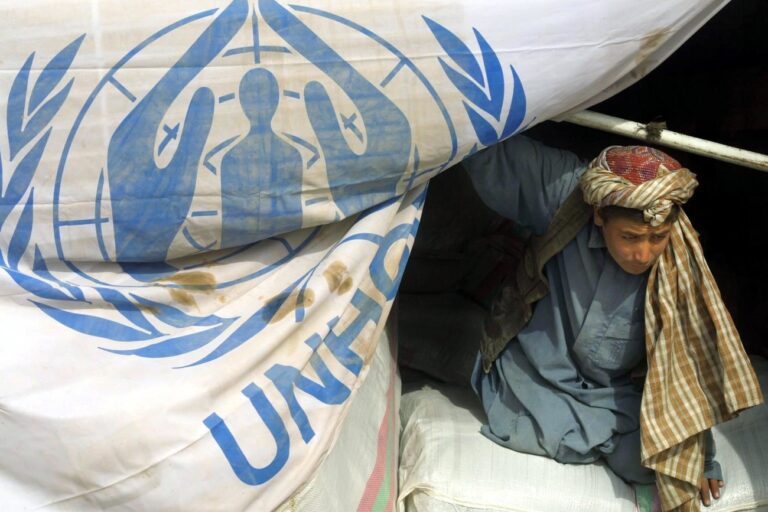 HER39 - 20011123 - HERAT, AFGHANISTAN : An Afghan refugee helps unload humanitarian aid brought by the United Nations High Commissioner for Refugees (UNHCR) and Iran's Red Cresent society to the Minarah camp, in the outskirts of the western Afghan city of Herat 23 November 2001. The trucks, three of which belong to the UNHCR and 12 to the Red Crescent, arrived from Iran, carrying material including 2,000 plastic sheets, 10,000 blankets and food supplies for more than 12,000 displaced people in the camp, which is sheltering 200,000 Afghan refugees. 
EPA PHOTO AFPI/BEHROUZ MEHRI/bm/mro