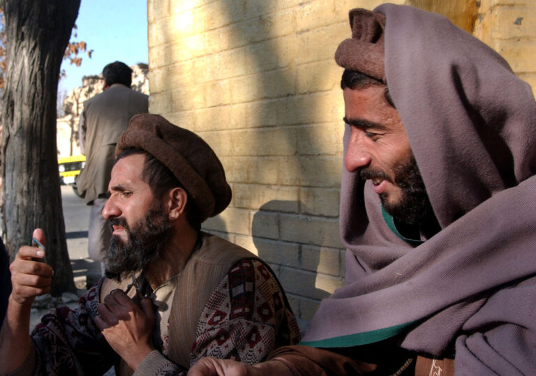 Jamshid, 50, left, trims his beard while he waits, with another former prisoner, in front of Kabul's Presidential Palace on Saturday, Dec.15, 2001. Jamshid, who was arrested by the Taliban in Mazar-e-Sharif in 1997, imprisoned in Kandahar and released Friday is asking to the former President of the Islamic Republic of Afghanistan Burhanuddin Rabbani, for shelter. (AP Photo/Marco Di Lauro)