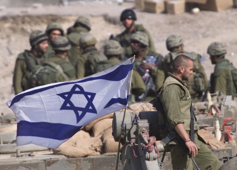 Israeli soldiers some atop armoured personnel carriers gather in the outskirts of the West Bank refugee camp of Jenin Friday April 12, 2002. The Israeli army said it would bury the bodies of Palestinian gunmen killed in the Jenin refugee camp during a 2-week-old hunt for militants in the West Bank. The decision prompted fresh Palestinian allegations Israel had killed hundreds of civilians and was trying to hide the bodies - something Israeli officials adamantly deny. (KEYSTONE/AP Photo/Lefteris Pitarakis)