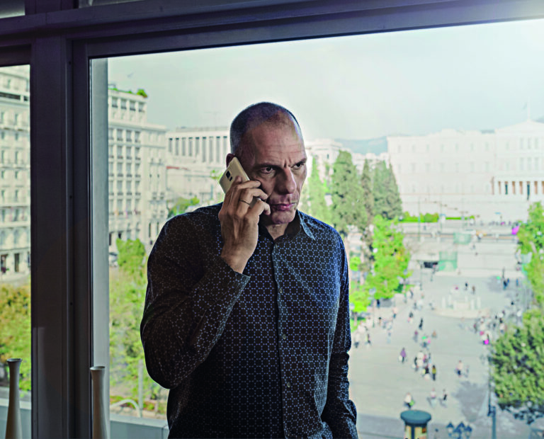 YANINS VAROUFAKIS  talking on the phone in his office that looks Syntagma Square