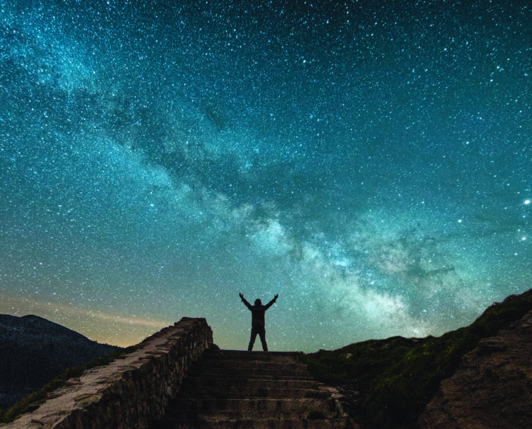 The milky way and the silhouette of a man with arms raised